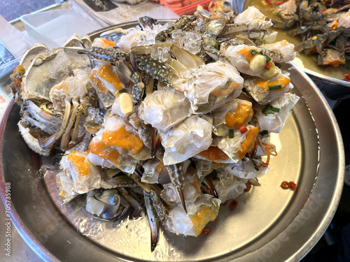 raw crab with roe marinated in fish sauce , pickled crabs with chilli are one of local famous menu of Thailand are displayed in stainless steel plate on the table in seafood market for the customers