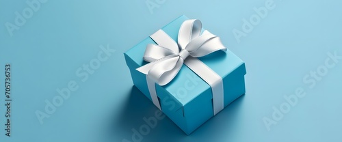 Luxury gift box with a blue bow on blue. High angle view monochrome closeup. Fathers day or Valentines day gift for him. Corporate gift concept or birthday party. Festive sale v5