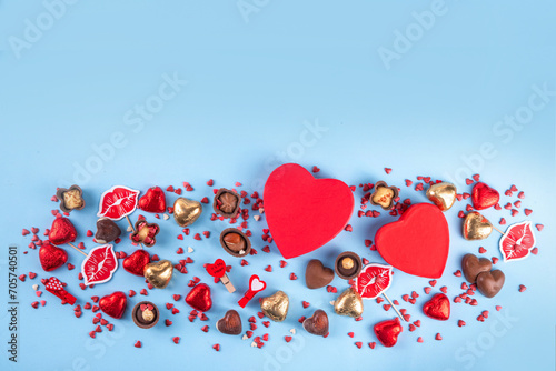 Valentine day celebration, invitation greeting card background with heart shape red, gold candy and chocolate sweets, gift box and on light blue background top view with copy space