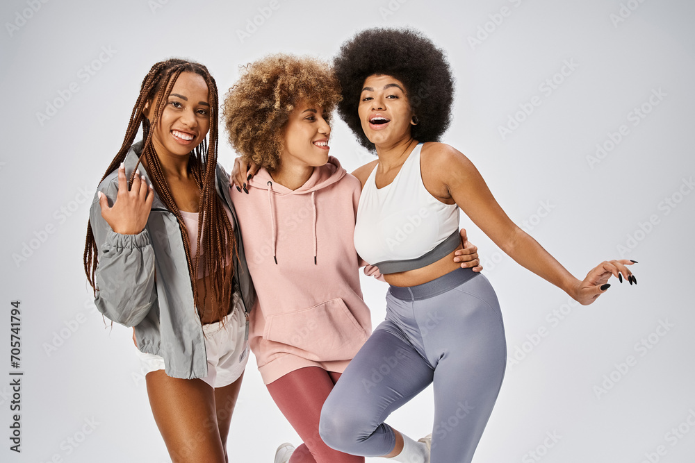 Obraz premium happy african american friends in sportswear posing on grey backdrop, Juneteenth celebration