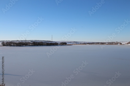 A snowy field with a city in the distance © parpalac