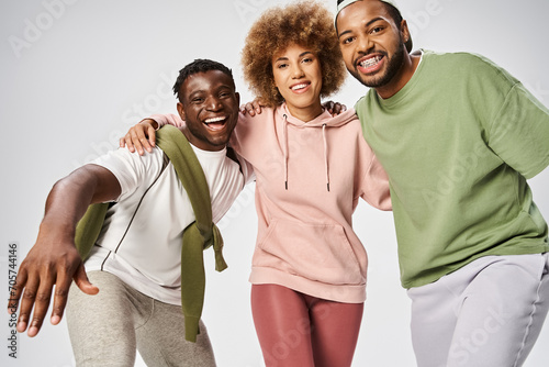 cheerful african american men and woman standing on grey background, Juneteenth celebration