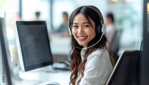 Smiling customer support operator with hands-free headset working in the office