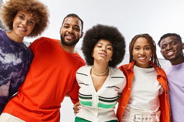 joyful african american woman hugging her friends in vibrant attire on grey background, Juneteenth