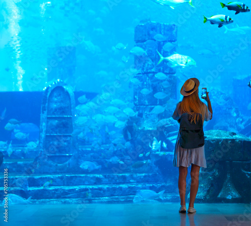 Sillouette of the woman taking picture in large aquarium