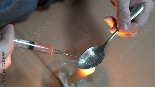 A drug addict cooks heroin on a spoon with the help of a candle fire. Drug addiction and homelessness concept. photo