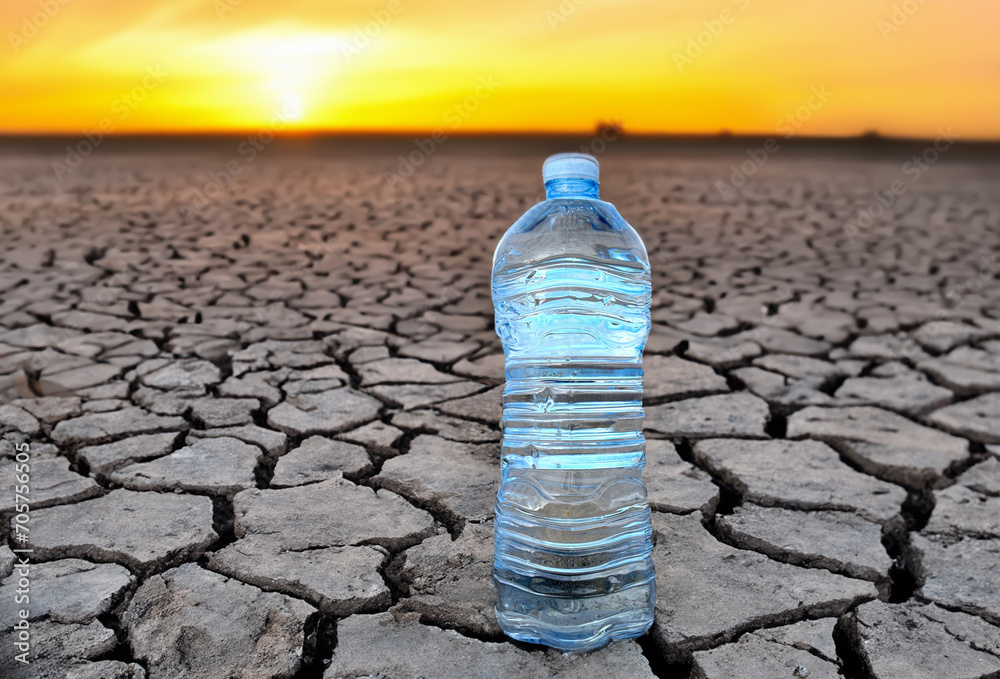 Mineral water on Drought land. Global drought. Plastic bottle with
