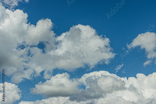 Background and textures of different and winding cloud formation in summer. Lots of clouds and sunshine during the day. Blue sky with cumulus clouds in sunlight.