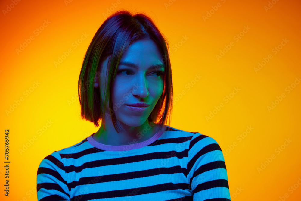 Portrait of young woman she squints eyes and looks away with contempt, suspicion against gradient orange background. Young woman thought something. Concept of beauty, human emotions, facial expression Portrait of young woman she squints eyes and looks away with contempt, suspicion against gradient orange background. Young woman thought something. Concept of beauty, human emotions, facial expression