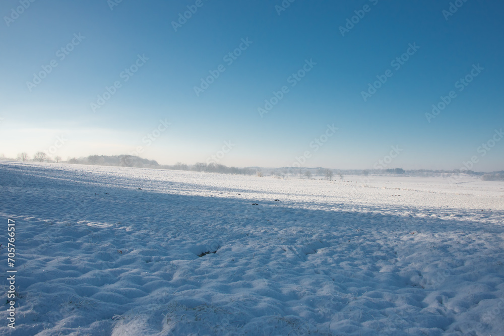 Norddeutsche Landschaft, schneebedeckt und friedlich an einem frühen Morgen in Kälte und Dunst