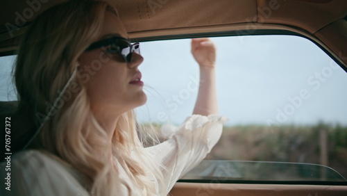 Carefree girl riding automobile putting hand in open window closeup. Driving car photo
