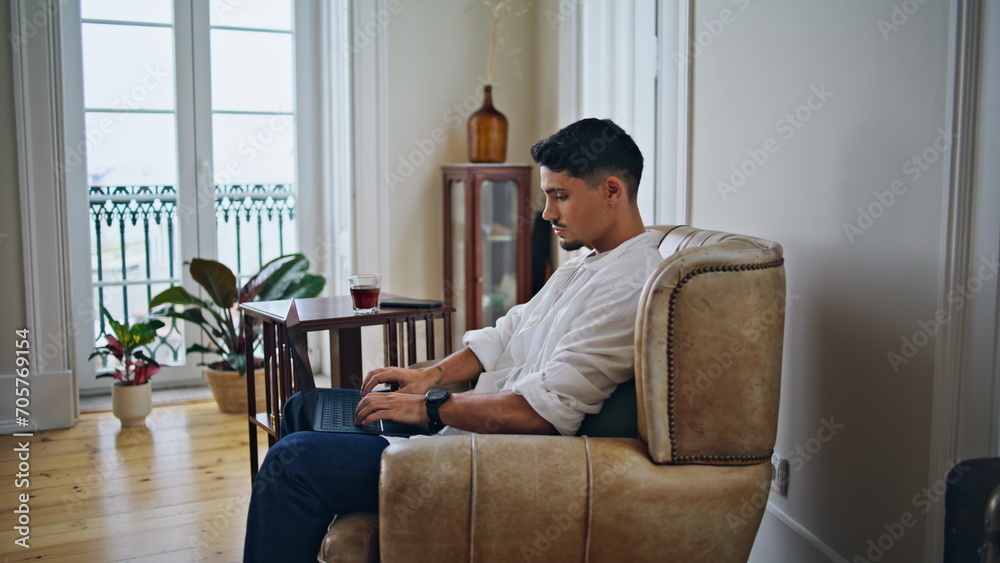 Calm man typing laptop at cozy apartment zoom on. Relaxed guy working remotely Calm man typing laptop at cozy apartment zoom on. Relaxed guy working remotely