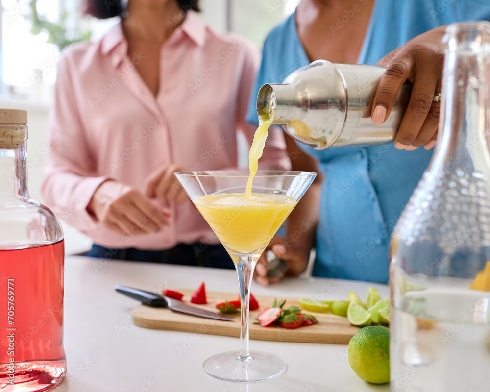 Close Up Of Female Friends At Home Having Fun Pouring Cocktails Into Glass Together Close Up Of Female Friends At Home Having Fun Pouring Cocktails Into Glass Together