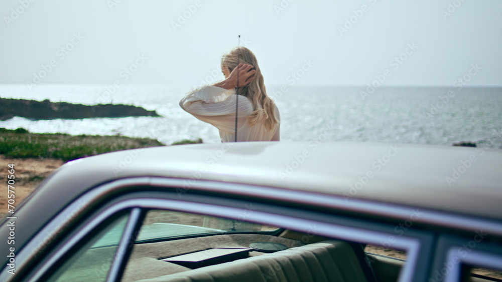 Woman walking retro car at sunny sea coast. Girl traveler relaxing on seashore.