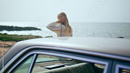Woman walking retro car at sunny sea coast. Girl traveler relaxing on seashore. © stockbusters