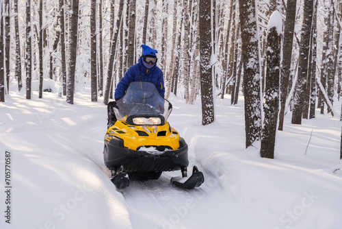 Woman on a snowmobile moving in the winter forest in the mountains of the Southern Urals