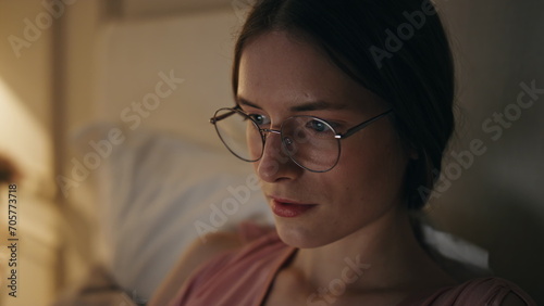 Closeup focused girl working home at night. Serious woman freelancer in glasses