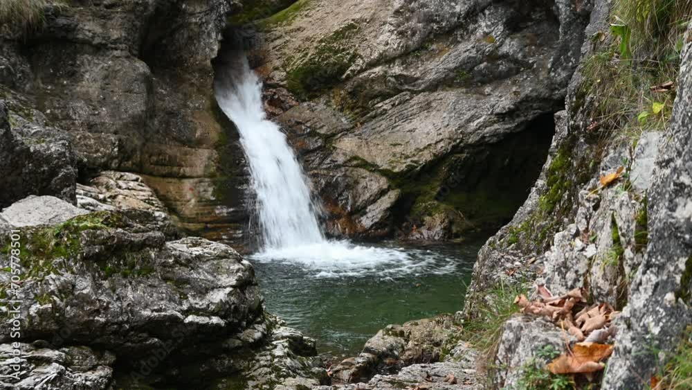 Waterfall flushes into a pond in autumn and leaves are falling Waterfall flushes into a pond in autumn and leaves are falling
