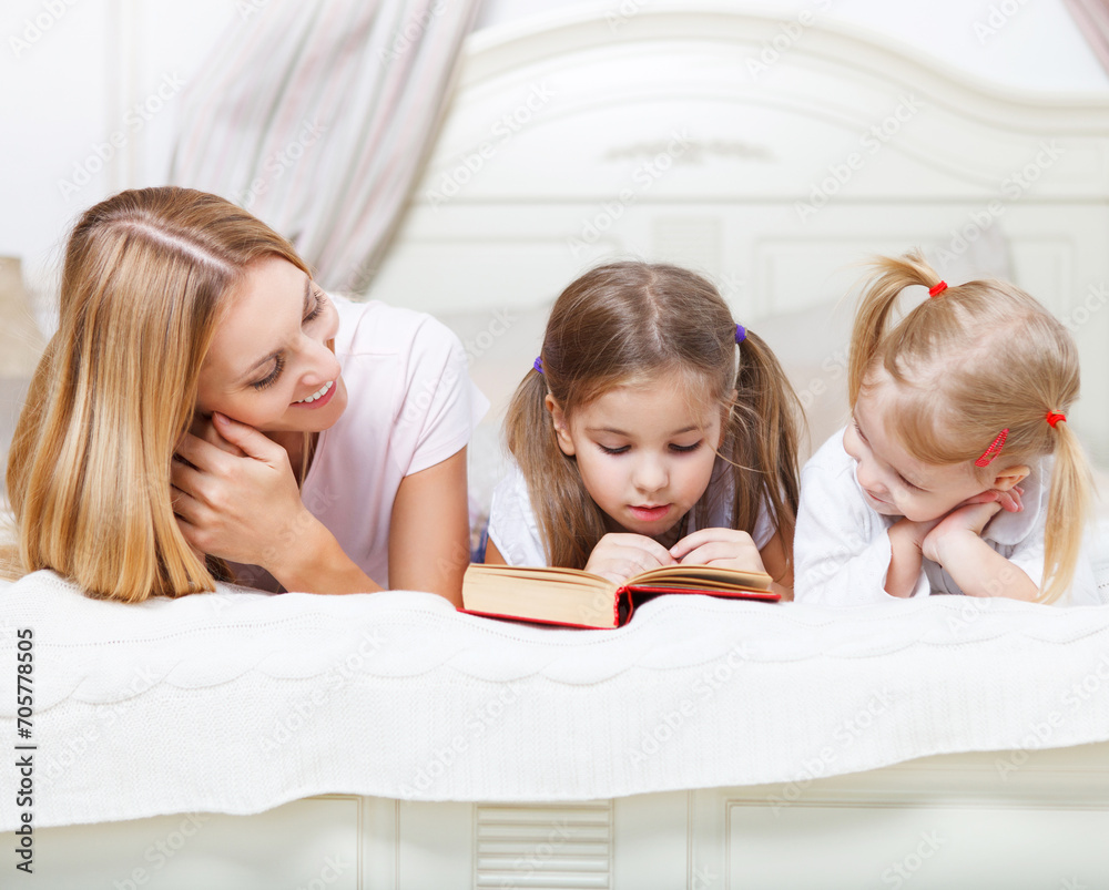 Mother and her daughters reading bed time story book Mother and her daughters reading bed time story book