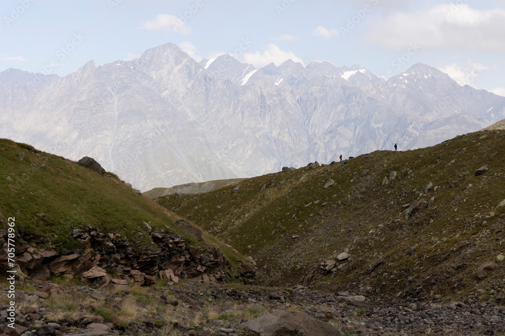 Group of tourists hiking in Caucasus mountains in Georgia on mount Kazbegi