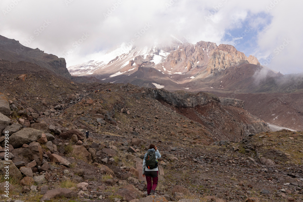 Woman trekking on mountain path in Georgia Caucasus mountains towards Kazbegi peak