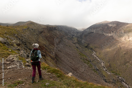 Woman trekking on mountain path in Georgia Caucasus mountains towards Kazbegi peak