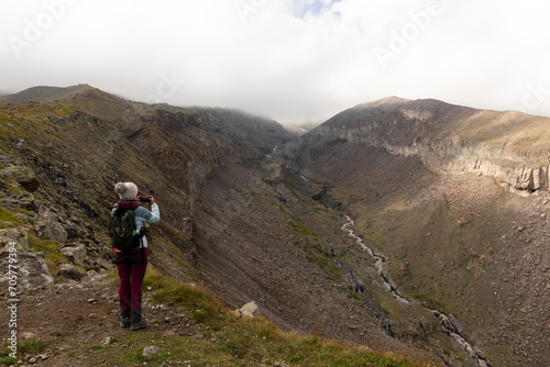 Woman trekking on mountain path in Georgia Caucasus mountains towards Kazbegi peak © Barosanu