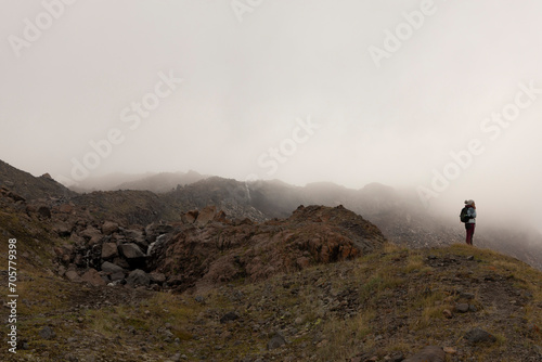 Woman on mountain meadow hiking in Caucasus mountains alone during summer foggy day