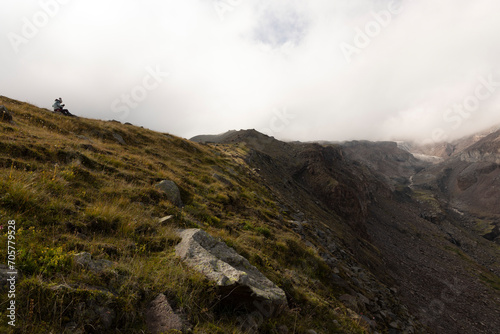 Woman on mountain meadow hiking in Caucasus mountains alone during summer foggy day © Barosanu