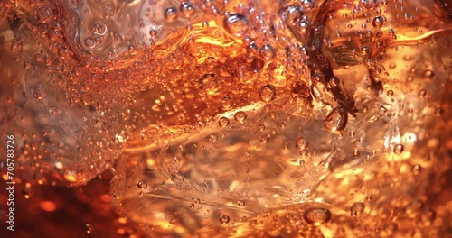 Super slow motion macro of ice cube is falling in campari or aperol spritz cocktail in transparent glass is being mixed by bartender in bar or club.