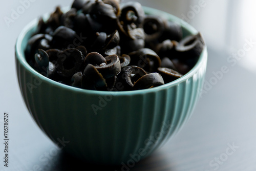 Cut Black Olives in Small Blue Bowl on Table - Savory Mediterranean Delight photo