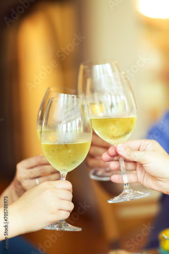 People cheering with white wine and rising glasses on celebration at restaurant