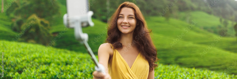 Selfie on smartphone of traveler woman during her travel vacation on famous nature landmark tea plantations in Sri Lanka. Fashion model outdoor photographing her self on cell phone camera. High Selfie on smartphone of traveler woman during her travel vacation on famous nature landmark tea plantations in Sri Lanka. Fashion model outdoor photographing her self on cell phone camera. High