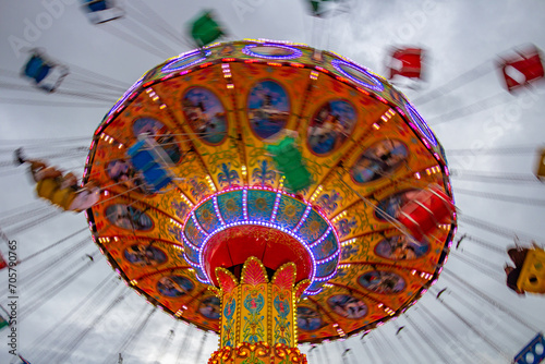 Um brinquedo gigante de rotação no parque de diversões com poucas pessoas, em um dia nublado. Foto feita de baixo para cima.