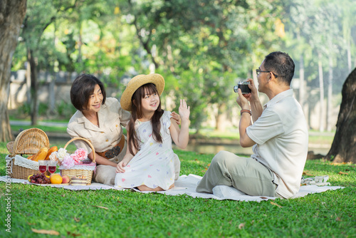 Asian family captures joyful moments during a sunny picnic.