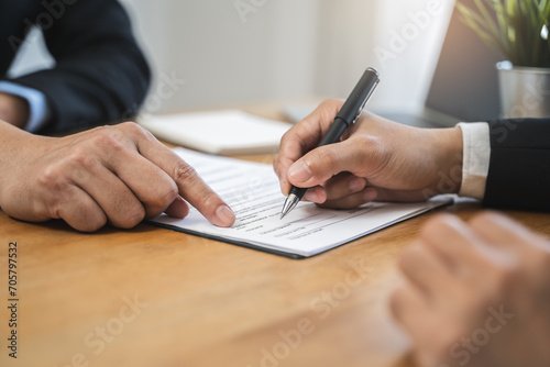 Fototapeta Naklejka Na Ścianę i Meble -  businessman sitting at desk holds pen signing contract paper, lease mortgage, employment hr or affirm partnership