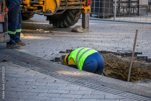 Maintenance workers on site repairing damaged water pipe under the street pavement