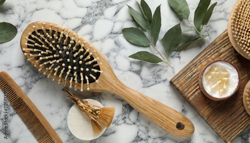 flat lay composition with wooden hair brush and comb on white marble table