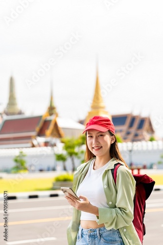 Young asian woman backpacker traveler with phone capturing moments and exploring Wat Phra Kaew and The Grand Palace in a happy and casual style during a sunny day © asean studio