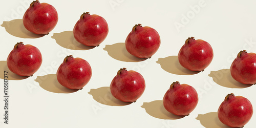 Isolated pomegranate fruits laid out diagonally in two rows against a beige background. Copy space, minimal food concept. Healthy nutrition.