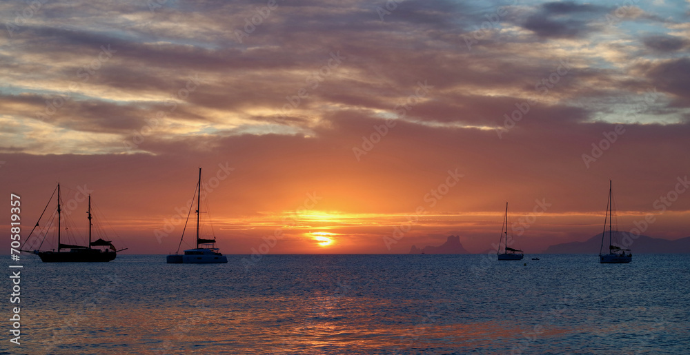 Wonderful sunset close to Ses Illetes beach in Formentera, Balearic Islands, Spain (no visible brand names or logos, only national flags on sailboats).