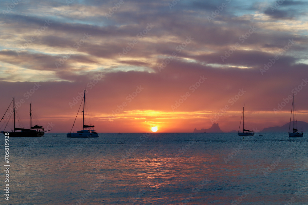 Wonderful sunset close to Ses Illetes beach in Formentera, Balearic Islands, Spain (no visible brand names or logos, only national flags on sailboats).