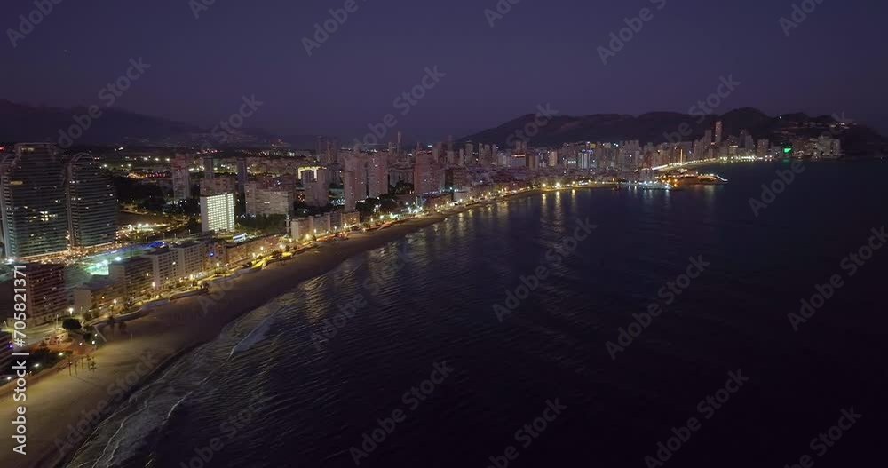 Aerial view of the coastal buildings at night in Benidorm, Spain. Beautiful blue hour aerial view of Benidorm. Peaceful beaches and smooth Mediterranean Sea with street lights glowing in the distance Aerial view of the coastal buildings at night in Benidorm, Spain. Beautiful blue hour aerial view of Benidorm. Peaceful beaches and smooth Mediterranean Sea with street lights glowing in the distance