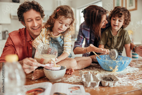 Family baking together in the kitchen with children making a mess photo