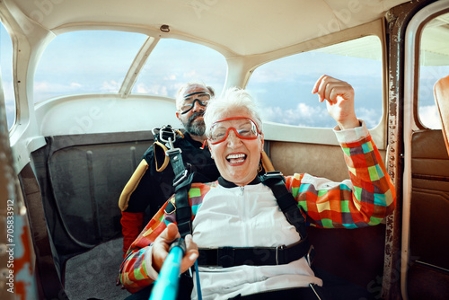 Senior woman skydiving with instructor in airplane photo