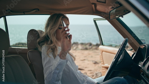 Stressed woman finish call sitting at car helm on seashore closeup. Girl worried