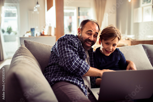 Excited father and little son using laptop at home