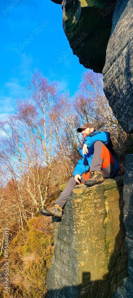 View of a man seated on a rock boulder from low angle view in a sunny winter day