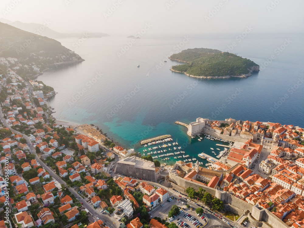 Aerial establishing shot of old town of Dubrovnik with island on Adriatic sea, Dalmatia, Croatia. Medieval city fortress with harbor and yachts. Drone view. Travel destination