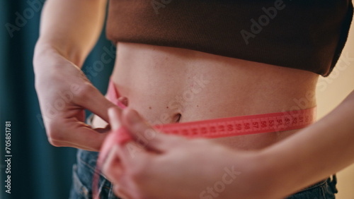 Hands measuring female waistline with tape closeup. Smiling happy woman enjoying